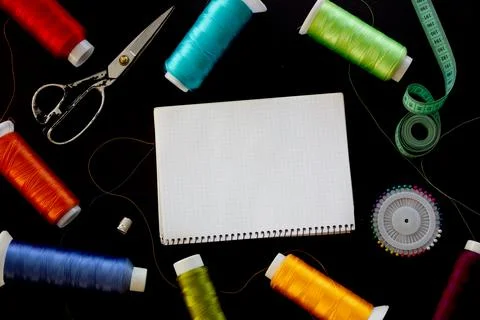 Sewing supplies and notepad for notes on a black background. Place for text. Foto stock