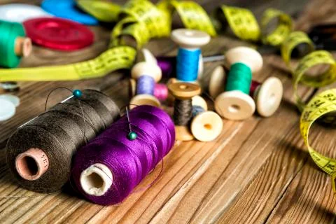 Sewing Supplies, Spools of thread, Buttons, Scissors, Measuring tape. On Wood Stock Photos