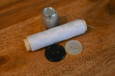 Sewing supplies with thread spool, thimble and buttons on wooden table Stock Photos