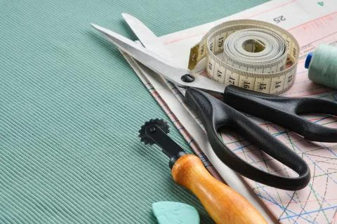 Sewing tailor items: scissors, measuring tape, spool of thread, patterns. Stock Photos