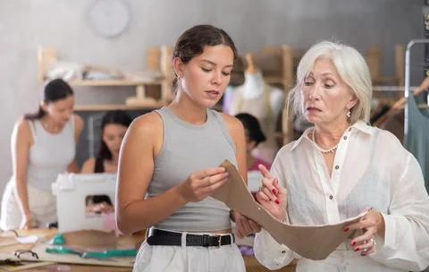 Sewing teacher reviewing pattern with student during class Stock Photos
