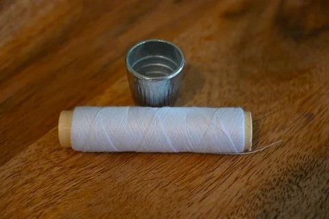 Sewing thimble and white thread on a wooden table Stock-Fotos
