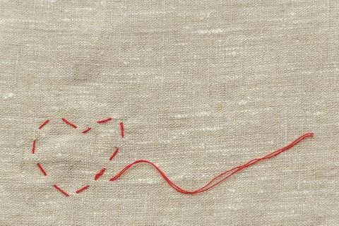 Sewing thread and for knitting, a red string in the form of a medical heart o Stockfoto's