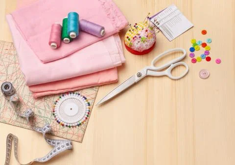 Sewing thread, spool of thread, pieces of cloth, buttons on wooden table Stock Photos