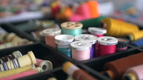 Sewing thread spools and bobbins of different colours in workshop tray Stock Footage 101647483