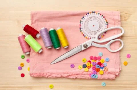 Sewing thread, threads, pieces of cloth, buttons on wooden table Stock Photos
