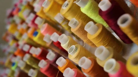 Sewing thread of warm colors in the coils hanging on the wall. Indoors, natural Stock Footage 80308311