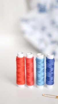 Sewing threads and measuring tape on white surface in neat composition.. Stock Photos