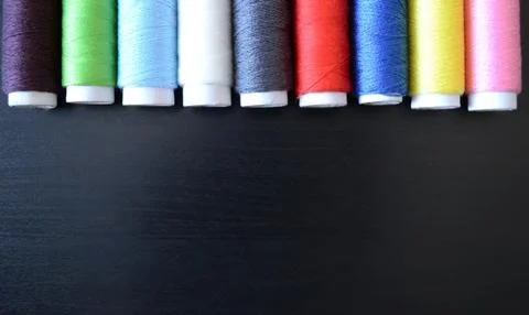 Sewing threads on a dark wood background, spools of thread, multicolored th.. Stock Photos