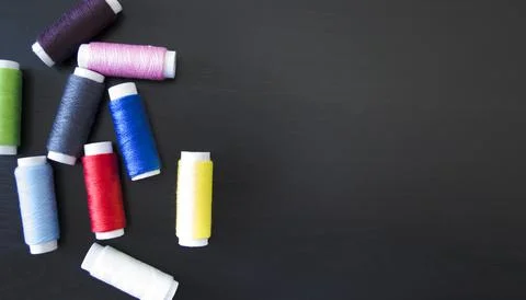 Sewing threads  on a dark wood background, spools of thread, multi colored .. Stock Photos