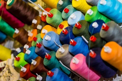 Sewing threads in many different colors on a performed metal wall. Sewing Stock-Fotos