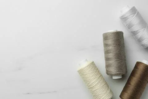 Sewing threads on white marble table, flat lay. Space for text Stock Photos
