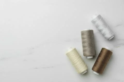 Sewing threads on white marble table, flat lay. Space for text Stock Photos