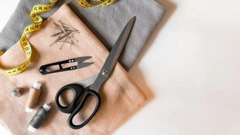 Sewing tools and fabrics. Scissors, thread, measuring tape, needles, and pins on Stock Photos