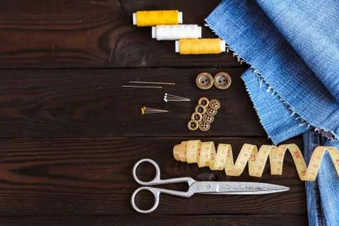 Sewing tools and materials scissors thread needles buttons lie on a dark wooden  Stock Photos