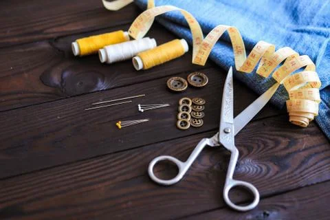 Sewing tools and materials scissors thread needles buttons lie on a dark wooden  Foto stock