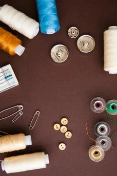 Sewing tools on the dark brown background with copy space in center Stock Photos