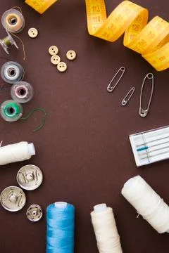 Sewing tools on the dark brown background with copy space in center Stock Photos