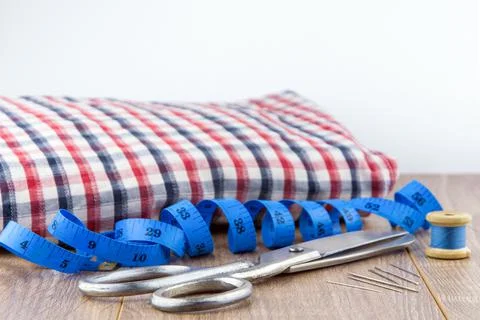 Sewing tools: large scissors, measuring tape, spool of thread and needles lie Stock Photos