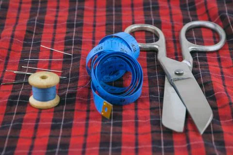 Sewing tools: large scissors, unwound measuring tape and thread with needles  Stock Photos