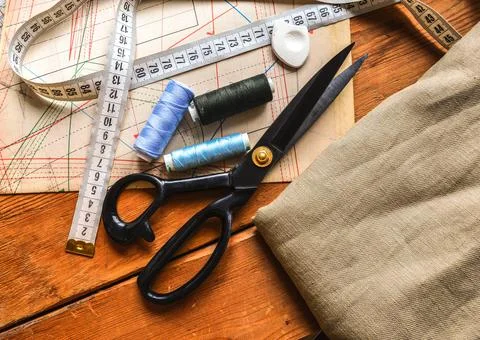 Sewing tools, scissors, spools of thread, measuring tape lie on tailors' diag Stock Photos