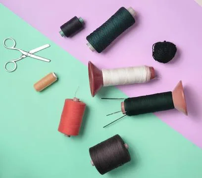 Sewing tools with thread spools and scissors on colorful background Foto stock