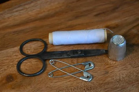 Sewing tools with white thread, scissors, thimble and safety pins on wood Stock Photos