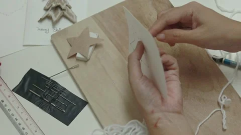 Sewing white yarn into a star shape pattern in making a handmade Christmas Stock Footage 311423771