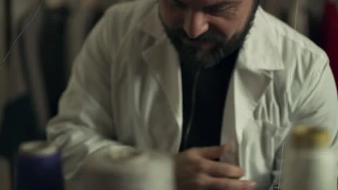In a sewing workshop, an Italian tailor uses a sewing machine to make clothing. Stock Footage 199456821