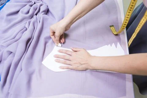 Sewing workshop. Seamstress at work. Marking and cutting fabric. Stock Photos