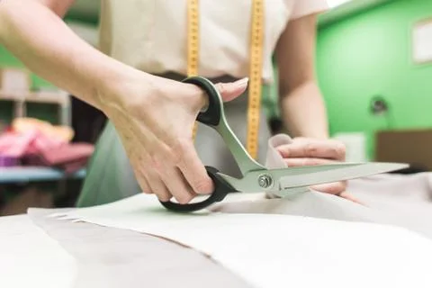 Sewing workshop. Seamstress at work. Marking and cutting fabric. Stock Photos