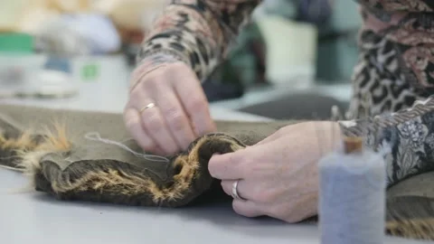Sewing workshop. Sewing two pieces of faux fur by hand. Sewing with a needle and Stock Footage 148110987