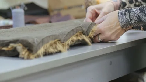 Sewing workshop. Sewing two pieces of faux fur by hand. Sewing with a needle and Stock Footage 150056156