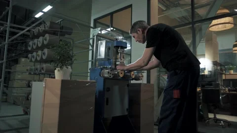 Sewing workshop worker sets up an automated machine for the production Stock Footage 179704027