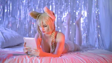 Sexual girl with big boobs is relaxing in bedroom, swaying legs, using tablet Stock Footage