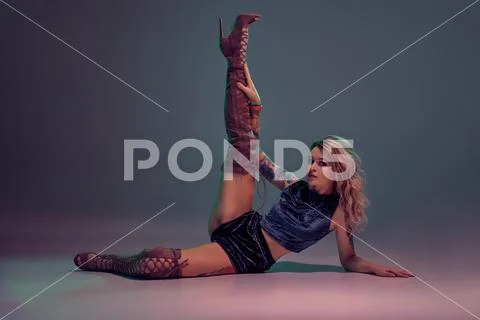 Sexy blond woman with tattoed body and long curly hair is dancing