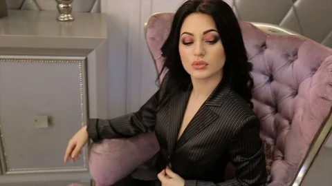 Sexy brunette posing while sitting in a chair. slow motion Stock Footage 72941913