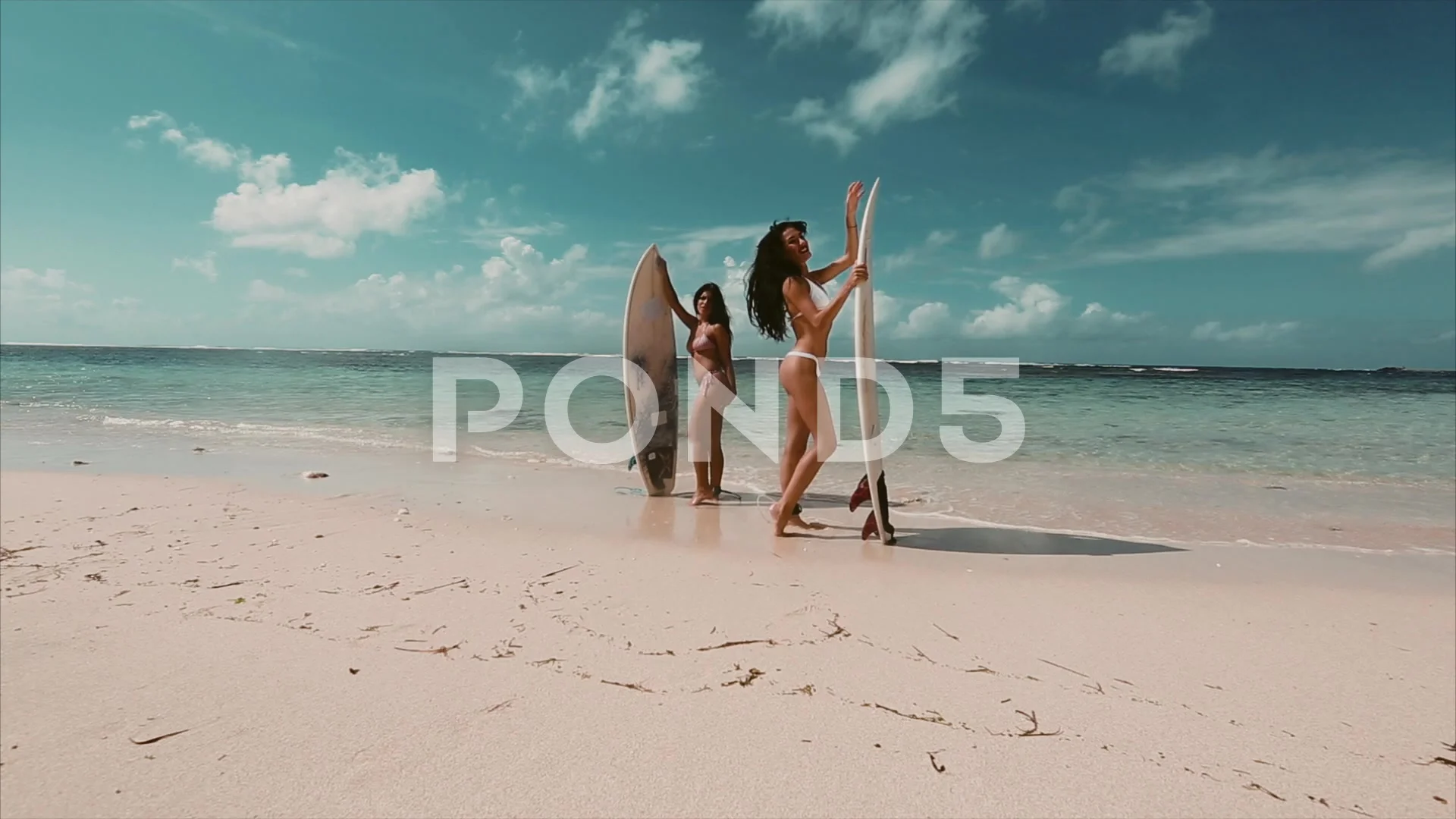 Sexy, brunette two girls with surf boards, dancing, having fun on the beach.