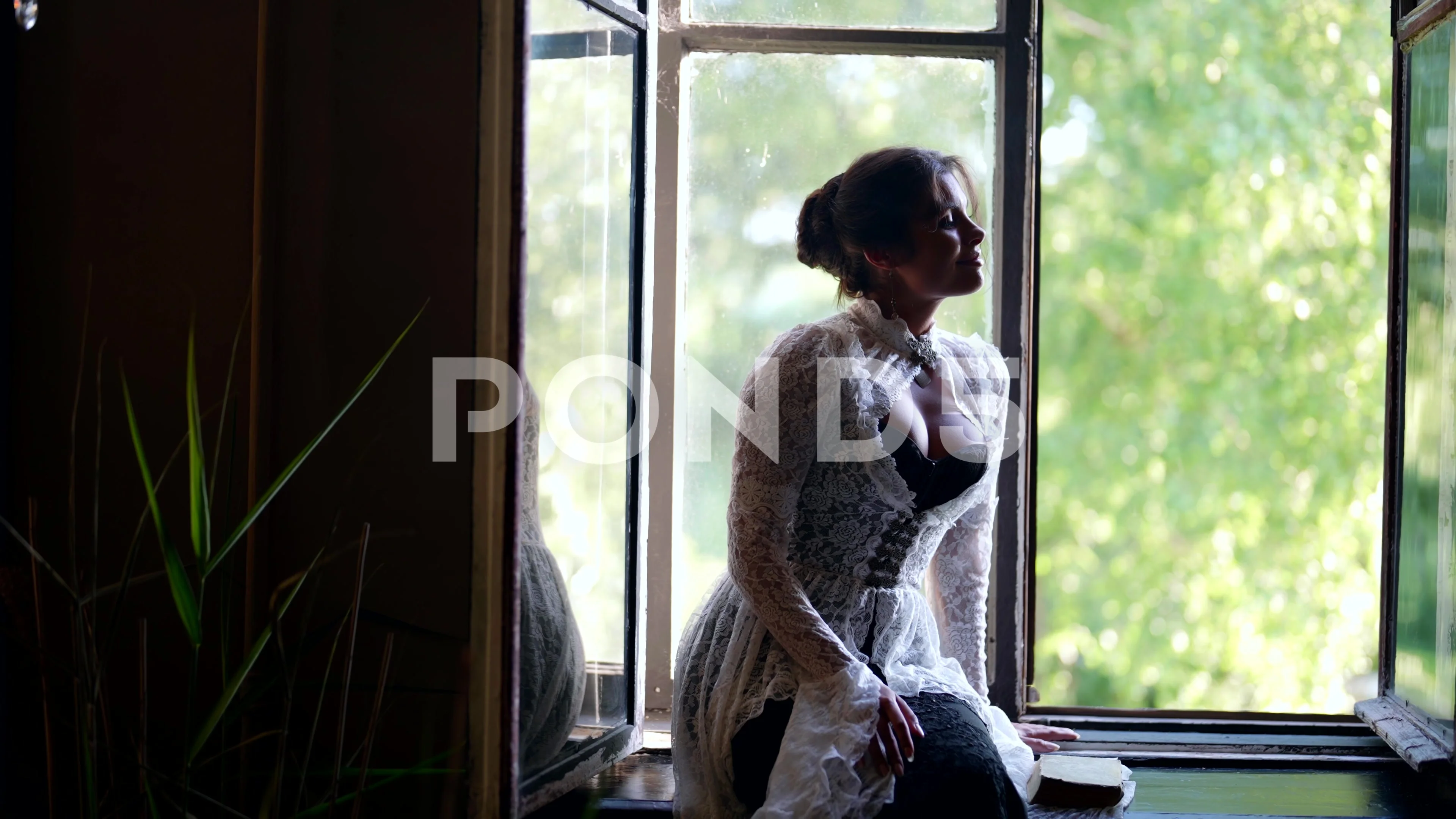 sexy busty woman in vintage gown sitting on windowsill of old house in  village