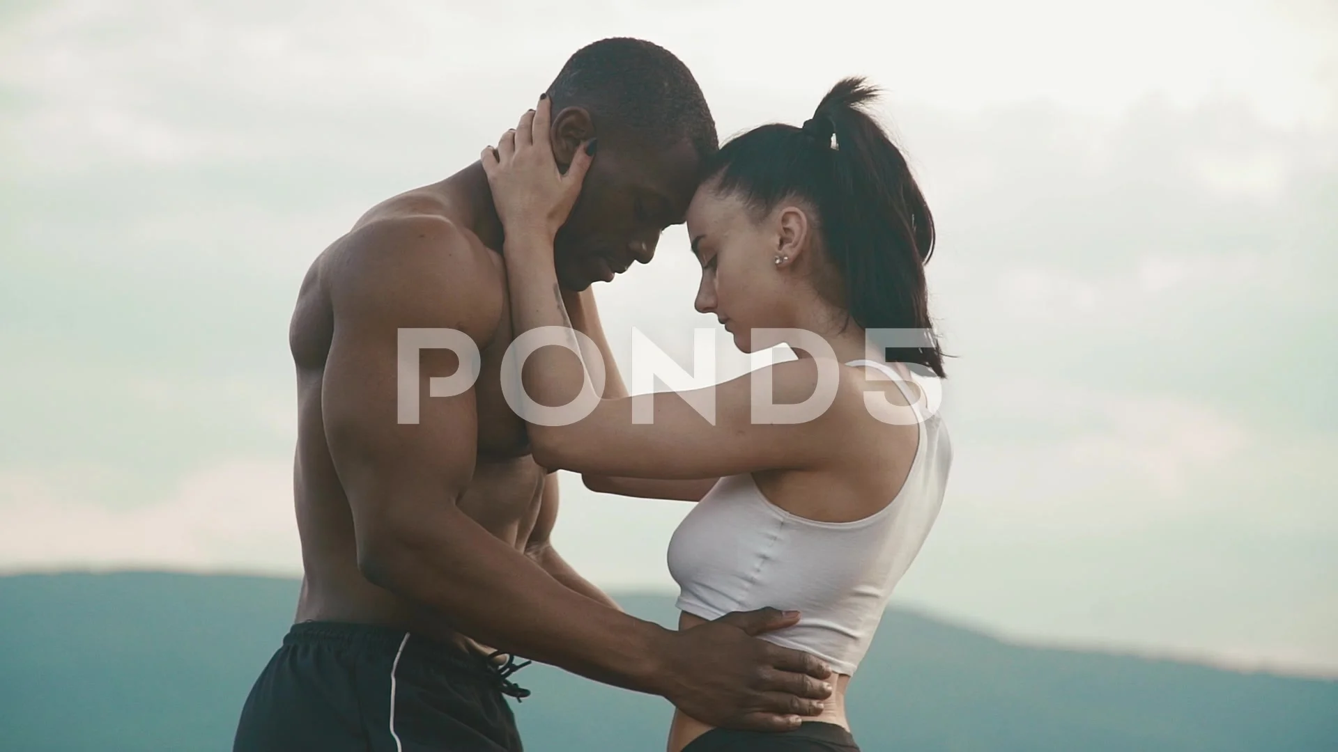 Sexy fit mixed race couple with perfect bodies in sportswear softly  embracing on