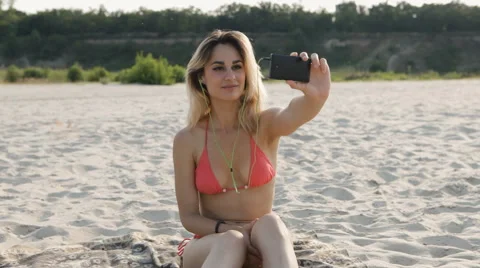 Sexy girl in pink bikini makes selfie on the beach Stock Footage