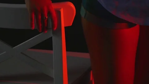 A sexy girl sits on a chair in a In short shorts and a shirt on black background Stock Footage