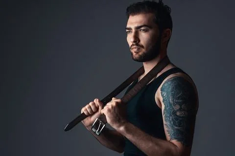 Sexy guy in studio on black background. Attractive man with belt. Stock Photos