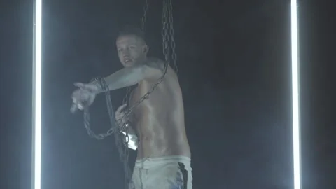 Sexy man dancing with chains in smoke Stock Footage 145883912