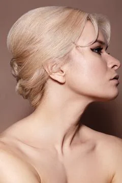 Sexy model with retro make-up, clean skin, blond hair on beige background Stock Photos