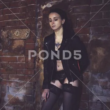 Sexy model stands old brick wall and poses in the image of a corrupt girl. Pr Stock Photos