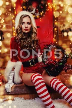 Sexy Santa girl in red body suit and striped stockings holds a basket in his Stock Photos