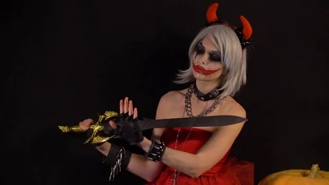 Sexy seductive devil girl makes manicure, cuts nails by sword, celebrate Stock Footage 81157720