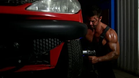 Sexy strong guy changes the wheel from car Stock Footage 75861502