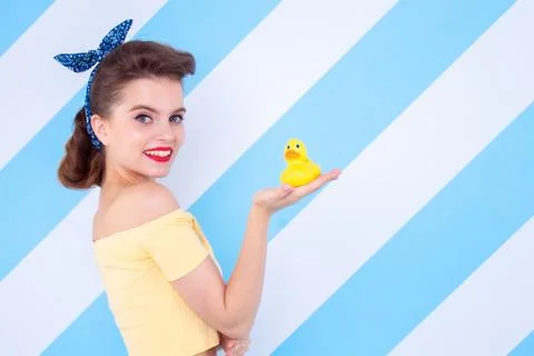Sexy surprised woman with rubber duck in hands and open mouth. Colorful backg Stock Photos